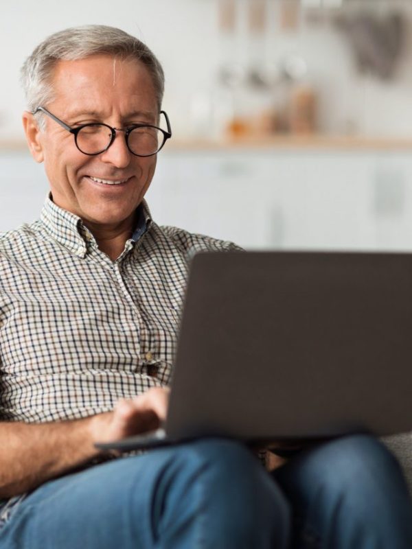 happy-senior-man-using-laptop-browsing-internet-sitting-at-home.jpg